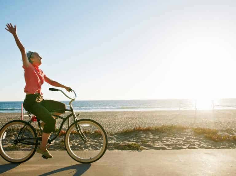 Caucasian woman riding bicycle near beach